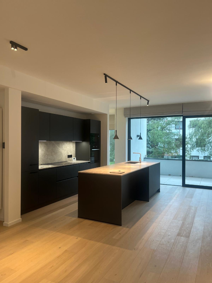 Photo d’un salon avec cuisine ouverte et grandes baies vitrées représentant un état des lieux d’entrée BEREX, garantissant transparence entre propriétaire et locataire.